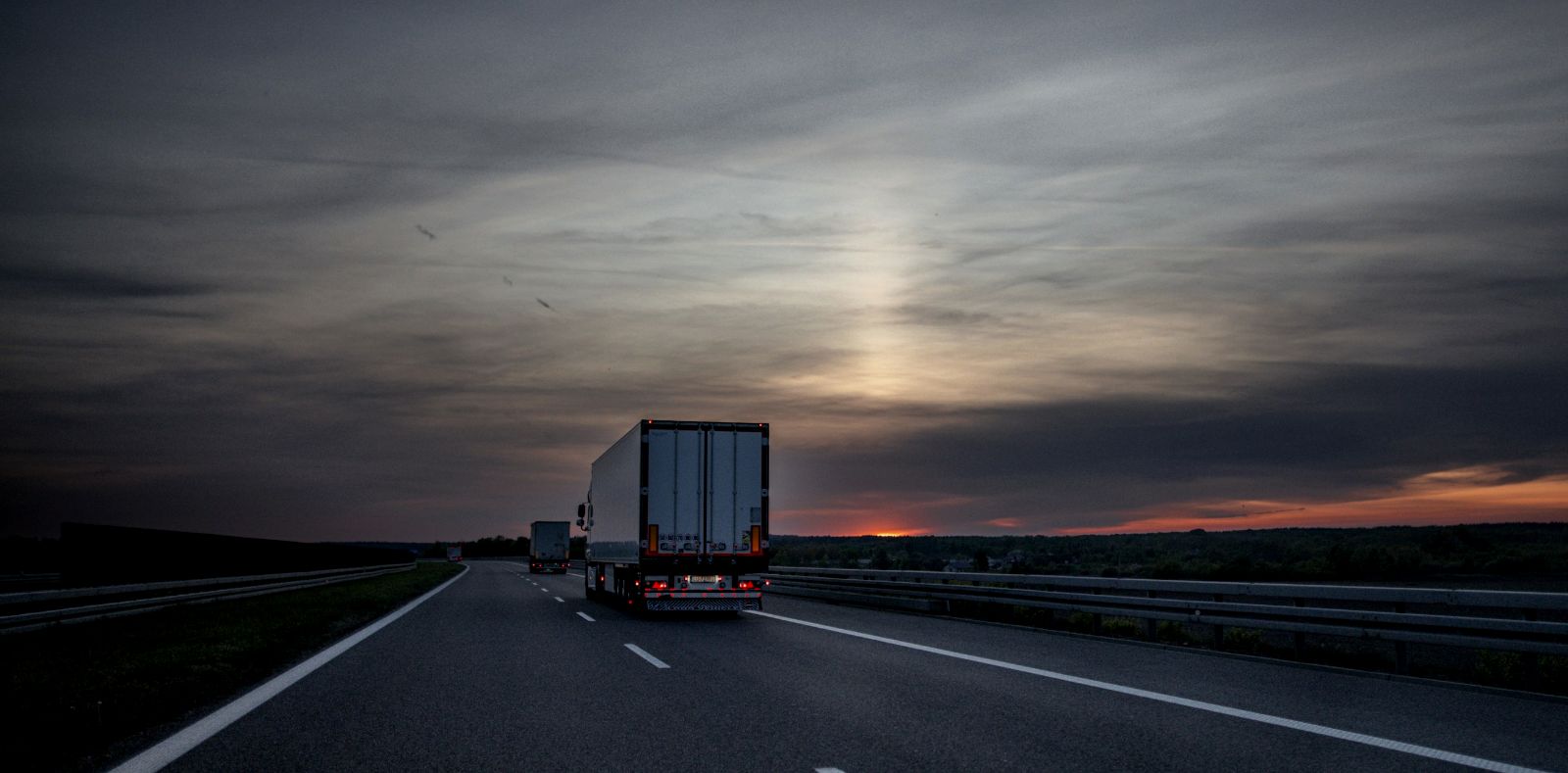 Camiones circulando por una autopista al anochecer